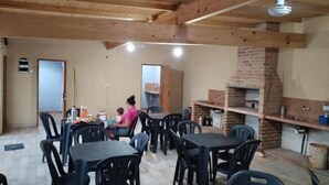 A dining area with tables and chairs, a brick oven, and a door in the background. - Department 2 (Puerto Iguazú)