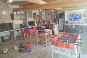 Una sala de estar acogedora con mesa de futbolín, chimenea y televisión.