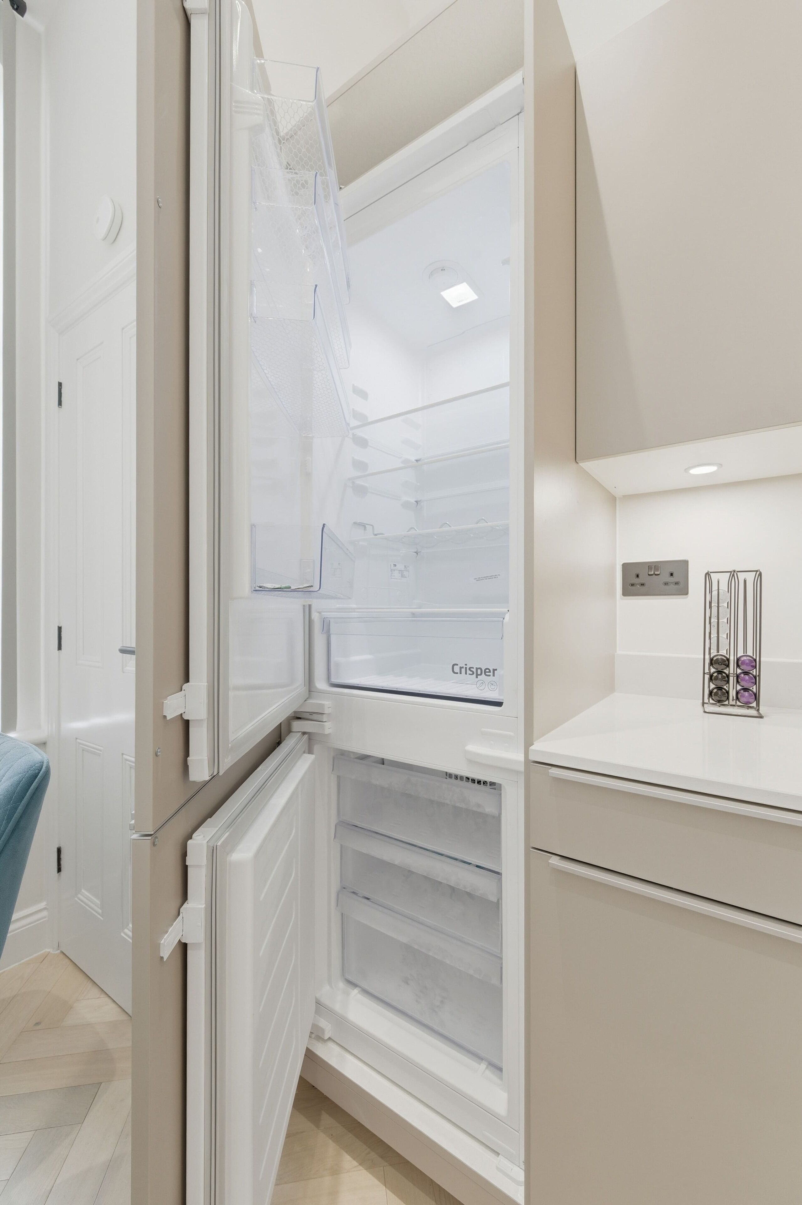 A modern kitchen with a built-in refrigerator, a countertop with a food container, and a wall-mounted light switch.