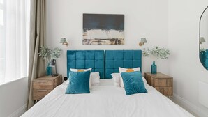 Una camera da letto con un letto grande, due comodini, una testiera, un quadro e due lampade a parete.