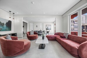 Een moderne woonkamer met een groot raam, een marmeren salontafel en rode banken.