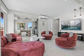 Ein modernes Wohnzimmer mit roten Samsofas, einem Flachbildfernseher und einem großen Fenster.