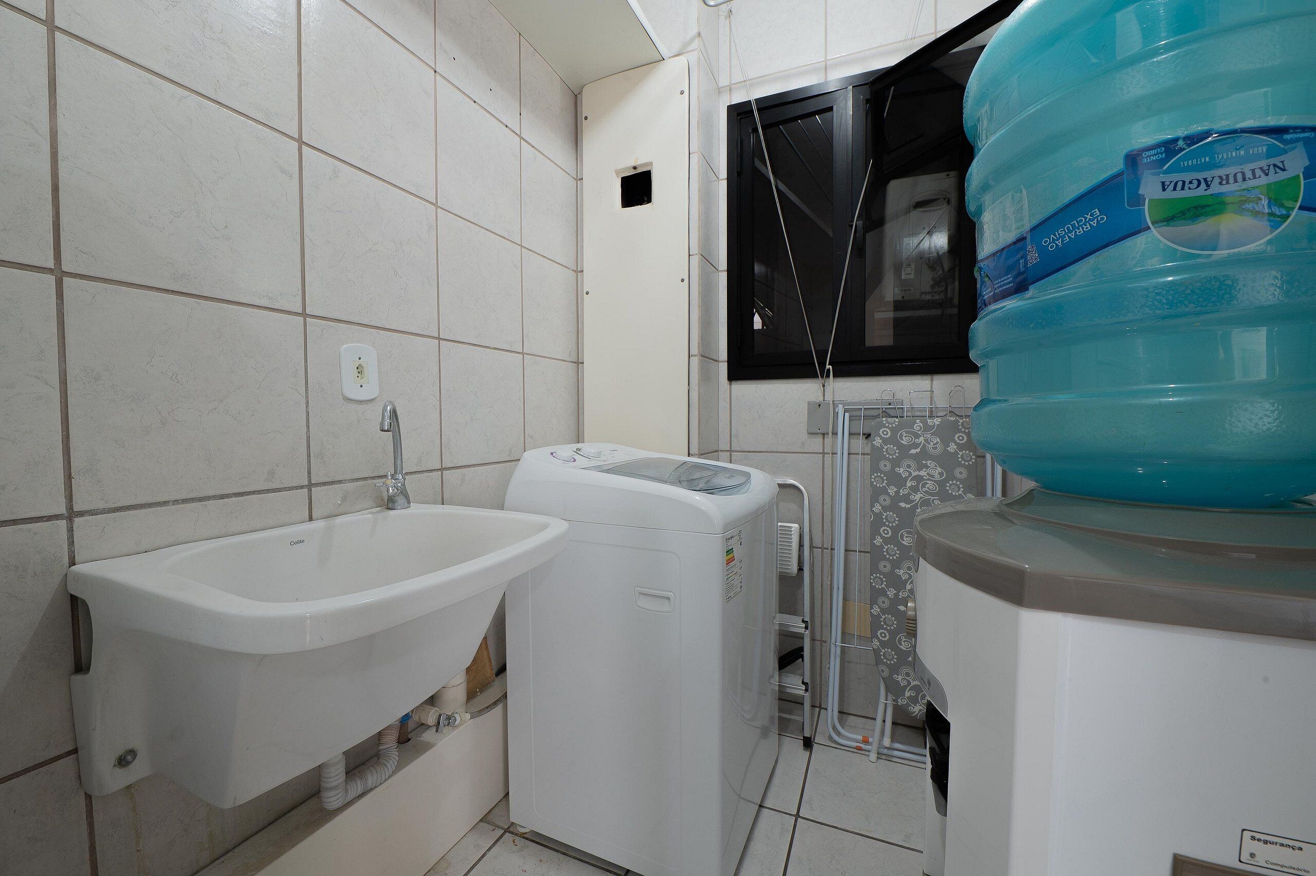 Un baño con lavamanos, lavadora y un dispensador de agua grande.