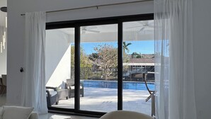 Ein modernes Wohnzimmer mit einem großen Schiebeglastür, die zu einem Poolbereich führt.