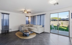 Una sala de estar moderna con un sofá modular, una mesa de centro y un ventilador de techo.