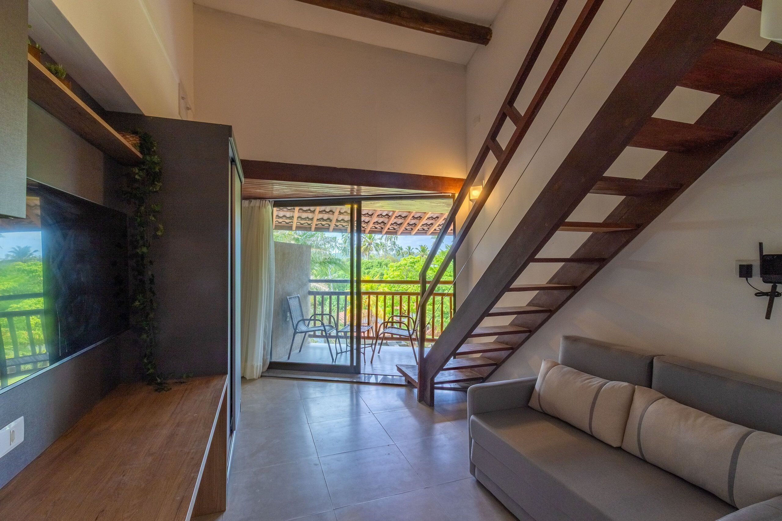 Un salon moderne avec un canapé, un téléviseur et un escalier menant à un balcon.