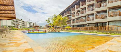 Un hôtel doté d’une piscine, d’un espace extérieur aménagé et d’un immeuble à plusieurs étages avec des balcons.