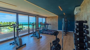 Ett gym med träningsutrustning, stora fönster och utsikt över havet.