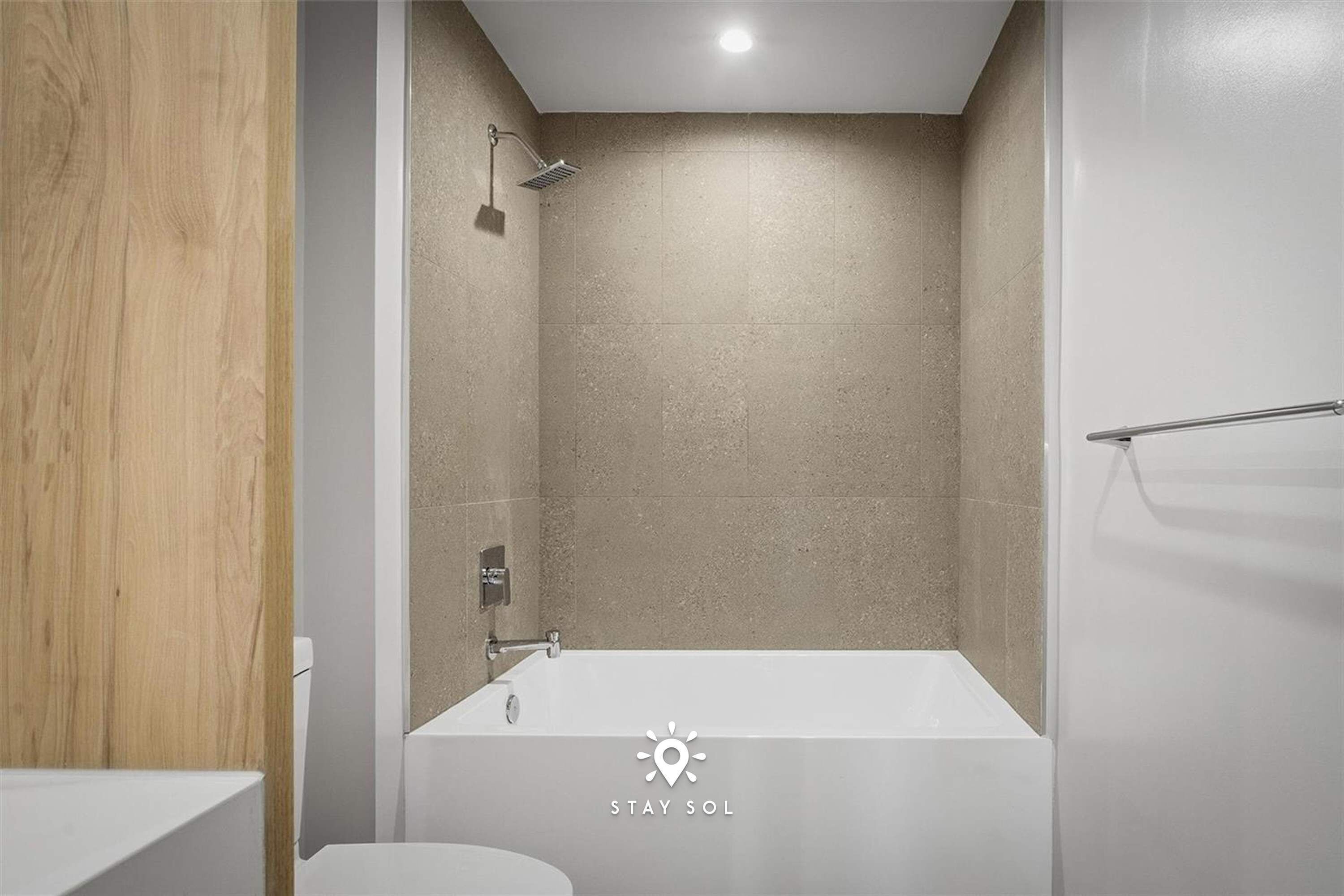 A modern bathroom with a bathtub, shower, and wooden paneling.