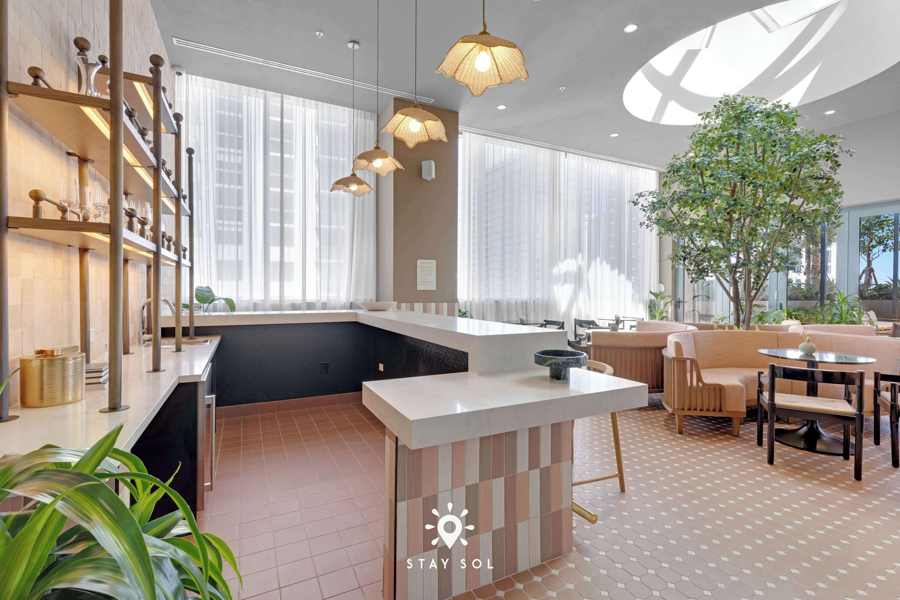 En modern hotellobby med en central ö, en sittgrupp och stora f önster.