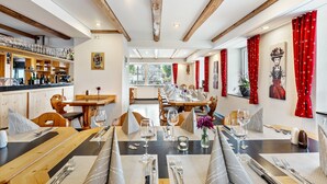 A restaurant with wooden beams, a bar area, and red curtains. - Speckhuisli – Mettmablick with Balcony, Breakfast, Sauna, Mountain View, Guesthouse (Grafenhausen)
