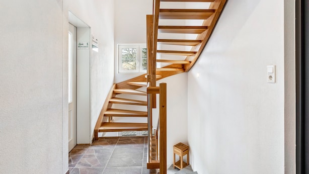 A wooden staircase in a hallway with a tiled floor and a small wooden stool. - Speckhuisli – Mettmablick with Balcony, Breakfast, Sauna, Mountain View, Guesthouse (Grafenhausen)