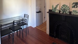 A room with a dining table and chairs, a fireplace, and a hallway leading to a door. - Updated 1BR apt, 1st floor, near T, free parking (Malden)