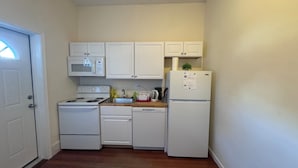 A compact kitchen with white appliances, including a stove, microwave, dishwasher, and refrigerator. - Updated 1BR apt, 1st floor, near T, free parking (Malden)