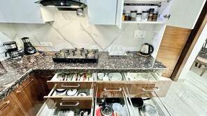 Eine Küche mit Gaskochfeld, Kaffeemaschine und Vorratseimern auf Regalen.
