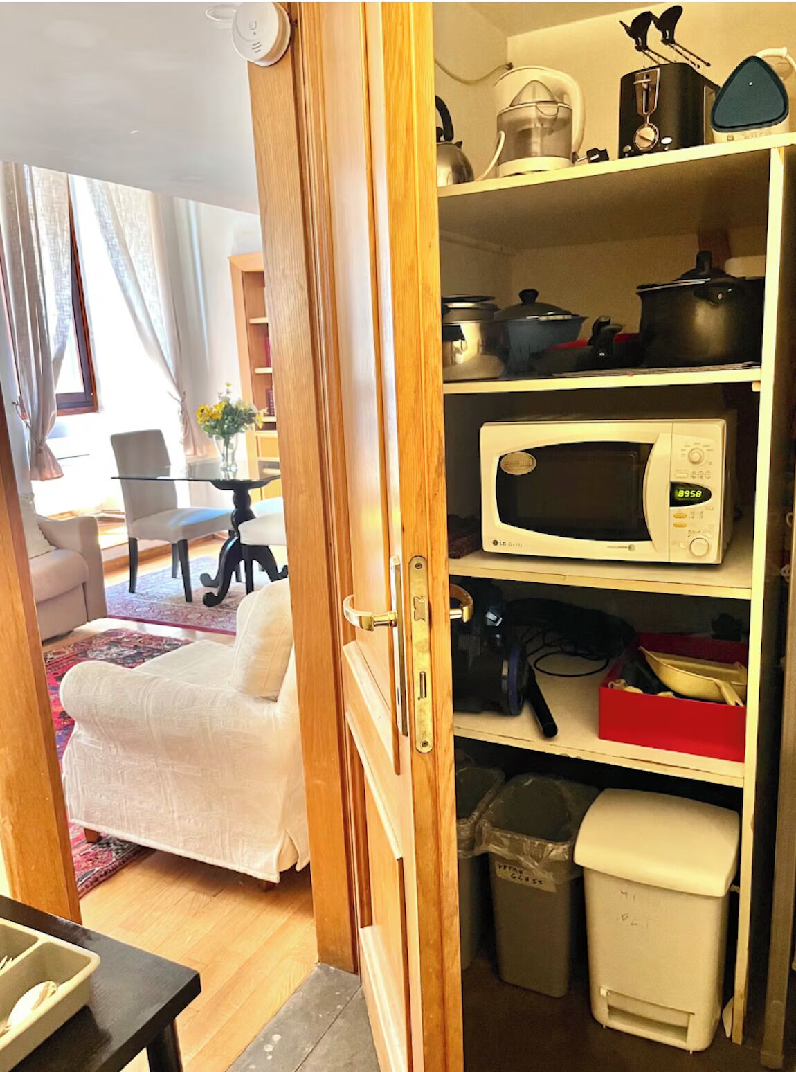 A compact kitchen with a microwave, a coffee maker, and a trash bin.