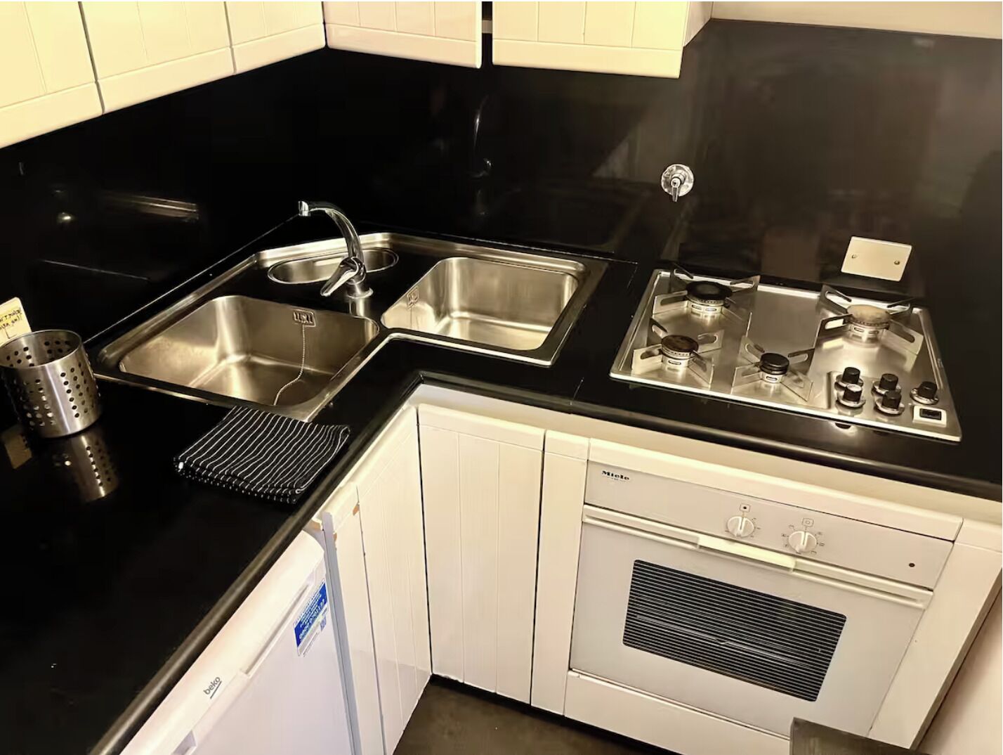 A compact kitchen with two stainless steel sinks, a built-in stove, and a dishwasher.