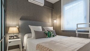 Un dormitorio moderno con una cama grande, una mesita de noche, una lámpara y una ventana con vistas.