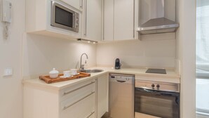 Una cocina compacta equipada con microondas, estufa, lavavajillas y fregadero.