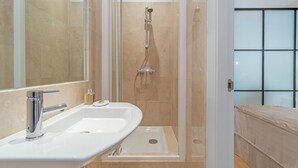 Un baño moderno con un espejo grande, un lavabo, una ducha y una bañera.