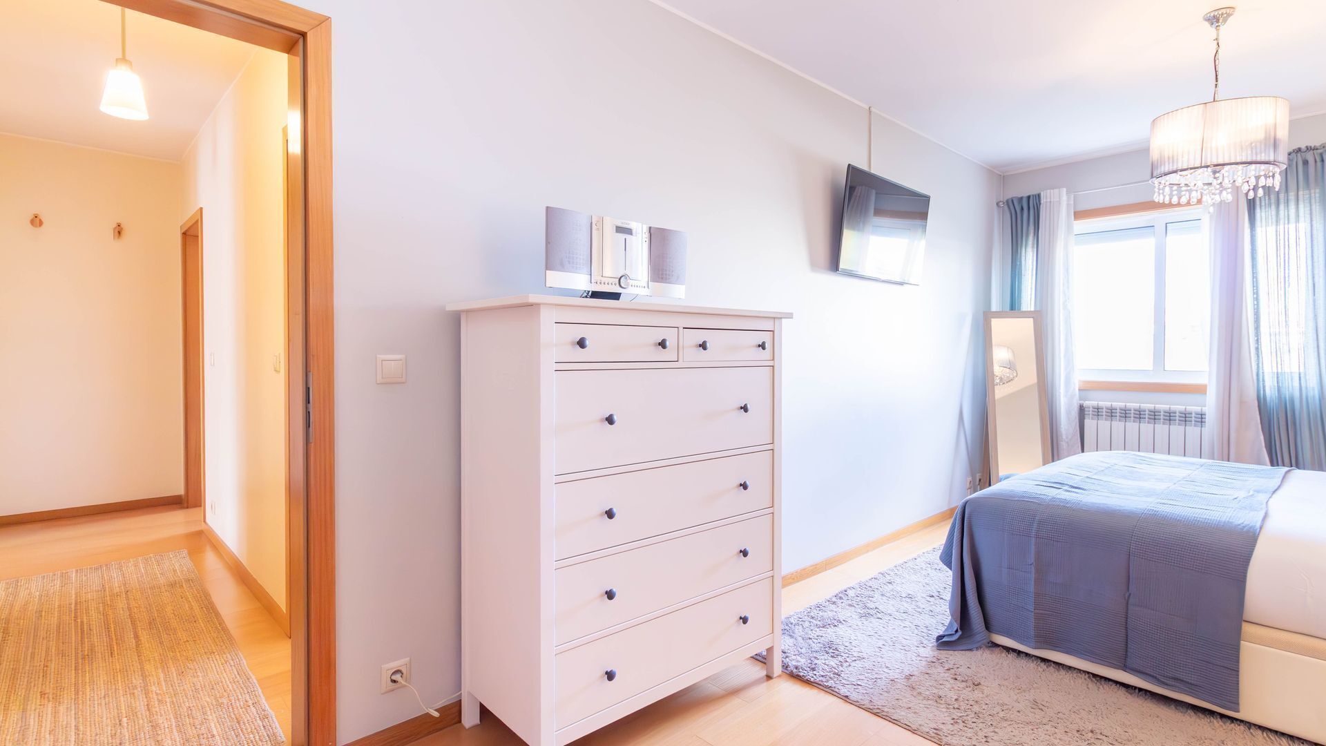 Una camera da letto con un letto, una cassettiera, una televisione e una finestra con tende.