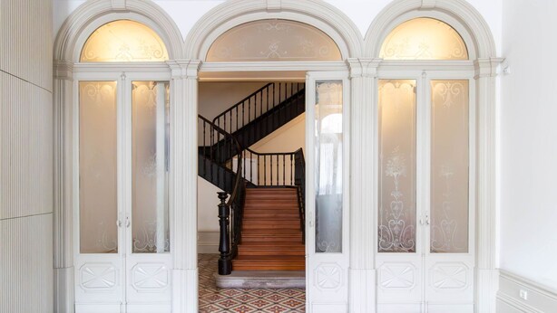 A grand staircase with a black railing leading to an upper floor, flanked by white doors with decorative glass panels. - B. Arts 1F by LovelyStay (Porto)