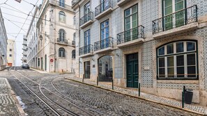 Een straat met tramrails, gebouwen met versierde gevels en een auto aan de kant van de weg.
