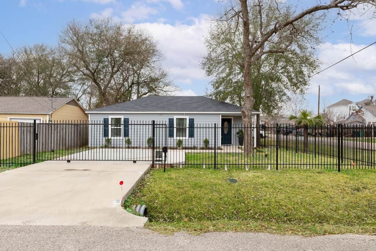 Una casa residencial con patio cercado, entrada para coches y buzón.