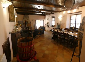 A rustic interior with a wooden ceiling, a dining area with a table and chairs, a large wooden barrel, and a giraffe statue. - Scappo in Umbria, Antico casale (Umbria)