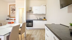 Une cuisine moderne avec des armoires blanches, un four encastré et une grande fenêtre.