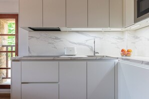 A kitchen with a marble backsplash, a built-in microwave, and a fruit bowl on the counter.