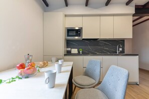 A modern kitchen with a built-in microwave, a marble countertop, and a dining area with a table and chairs. - InfinityCoast 3 byFidalsa (Piélagos)
