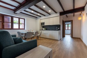 Une cuisine moderne avec des meubles blancs, un plan de travail en marbre et un coin repas comprenant une table et des chaises.