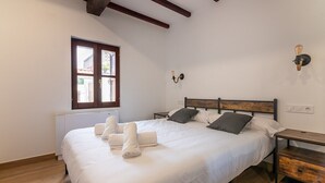 Un dormitorio con cama, mesitas de noche, una ventana y un aplique de pared.