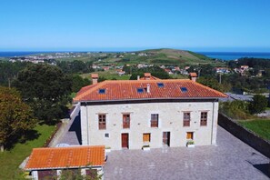 A stone building with a red-tiled roof, multiple windows, and a view of a coastal landscape. - InfinityCoast 3 byFidalsa (Piélagos)