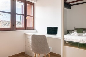 A bedroom with a bed, a desk with a laptop, a chair, and a window with a view of the outside. - InfinityCoast 3 byFidalsa (Piélagos)