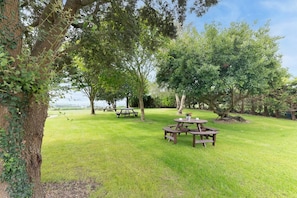 A grassy outdoor area with picnic tables and trees. - InfinityCoast 3 byFidalsa (Piélagos)
