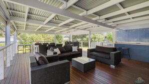 Un espacio de estar al aire libre cubierto con mobiliario de mimbre y una terraza de madera.