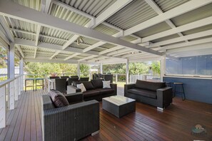 Ein überdachter Sitzbereich im Freien mit Korbmöbeln und einer Holzterrasse.