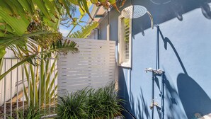 Una casa azul con valla blanca, una ventana y un cabezal de ducha metálico.
