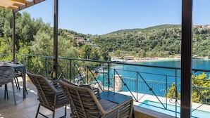 Eine Terrasse mit Korbmöbeln, einem Pool und Blick auf einen See und Hügel.