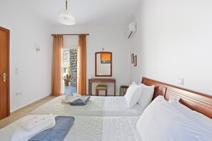 Habitación de hotel con cama, escritorio, espejo y vistas al exterior.