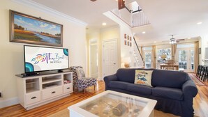 Una sala de estar con televisión, un sofá, una mesa de centro y una escalera que lleva a otro nivel.