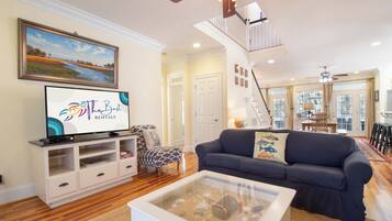 A living room with a television, a sofa, a coffee table, and a staircase leading to another level.