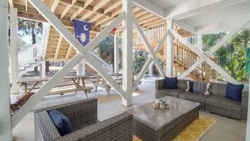 An outdoor covered patio area with wicker furniture, a flag, and a view of the surrounding landscape.