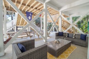 Un espace extérieur aménagé en patio, abrité et doté de meubles en osier, d’un drapeau et offrant une vue sur le paysage environnant.