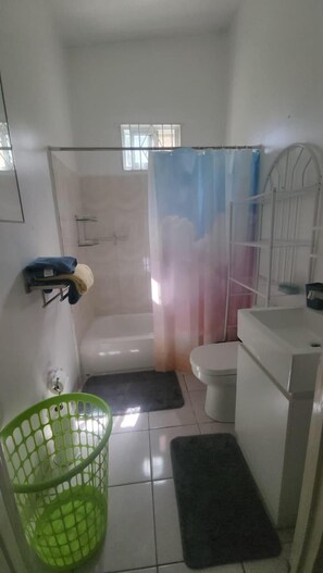 Une salle de bain avec une baignoire, des toilettes et un rideau de douche.