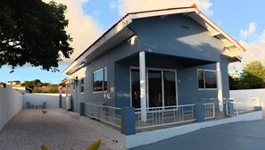 A single-story building with a blue exterior, white railings, and a covered patio area. - Casa Trini Central Curaçao | 3BR + AC + Parking (Willemstad)