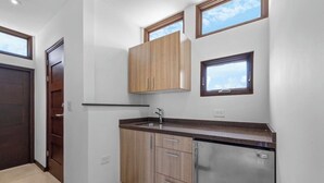 Eine kleine Küche mit Holzschränken, einem Edelstahlkühlschrank und einem Fenster über der Spüle.