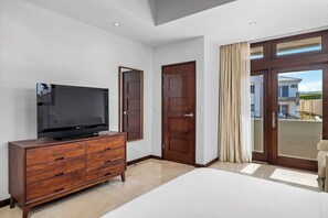 Ein modernes Hotelzimmer mit einem großen Flachbildfernseher auf einer Holzkombie, einem großen Bett und einer Schiebetür zu einem Balkon.